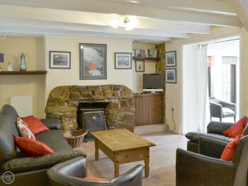 WOODEN FLOORS, EXPOSED BEAMS AND A FEATURE FIREPLACE MAKE THE LIVING ROOM A UNIQUE SPACE