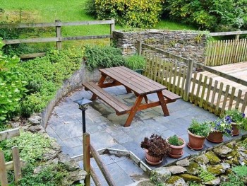 CHARMING TERRACED GARDEN TO THE REAR OF THE COTTAGE WITH A LARGE PICNIC TABLE AND BENCH
