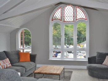 THE HUGE FLOOR TO CEILING ARCHED WINDOW IN THE LVING AREA AFFORDS VIEWS OF THE RIVER