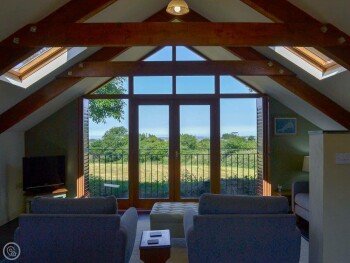 LARGE WINDOWS IN THE OPEN PLAN LIVING SPACE OFFER STUNNING COUNTRYSIDE VIEWS