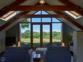 LARGE WINDOWS IN THE OPEN PLAN LIVING SPACE OFFER STUNNING COUNTRYSIDE VIEWS